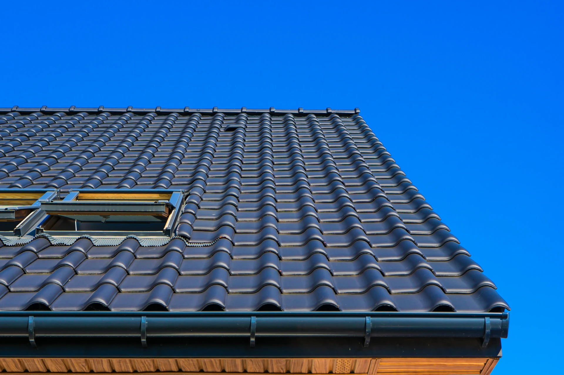 Fresh interlocking tiles laid in straight courses on a replacement pitched roof