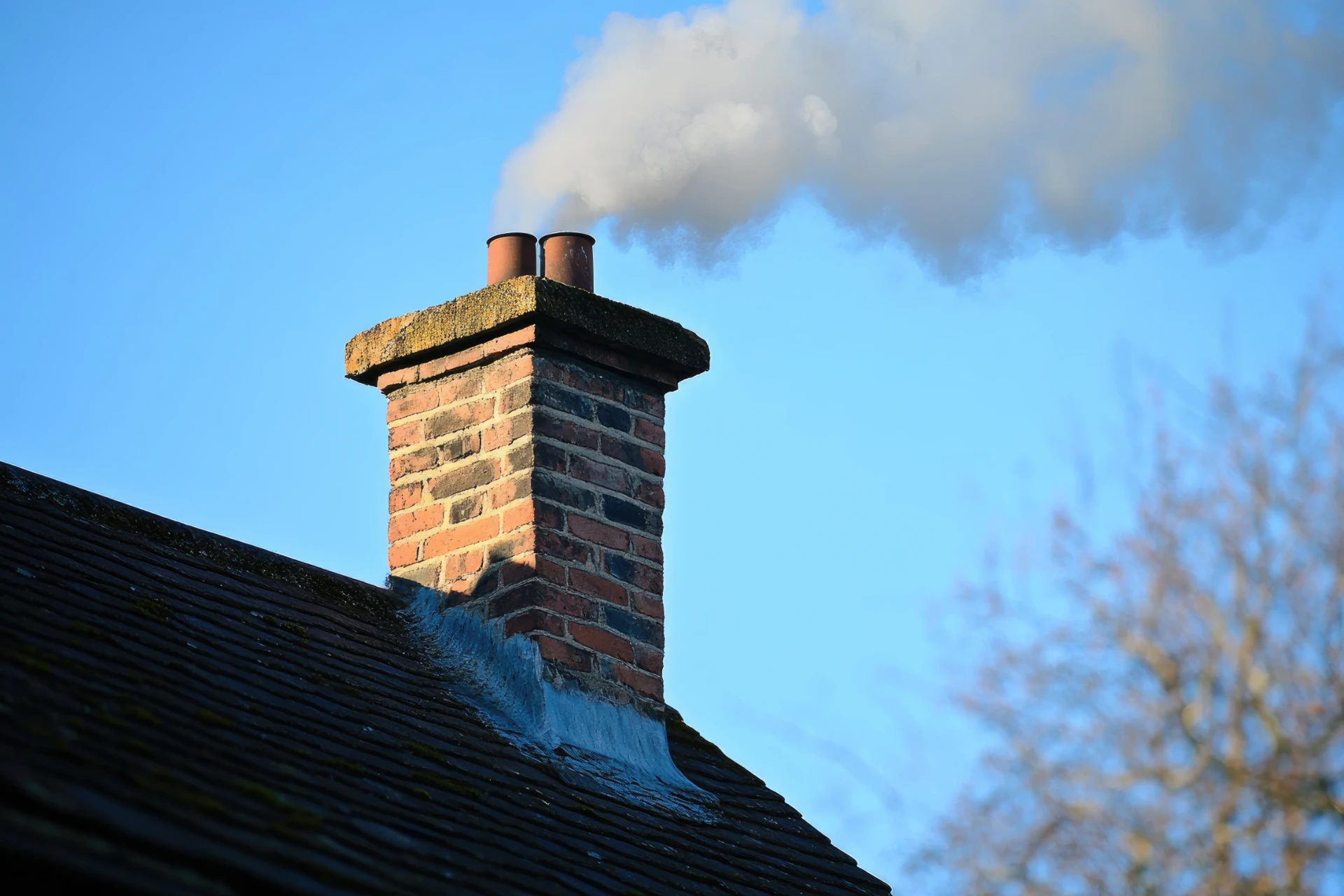 In-use brick chimney on a tiled roof showing its pots and flaunching in detail